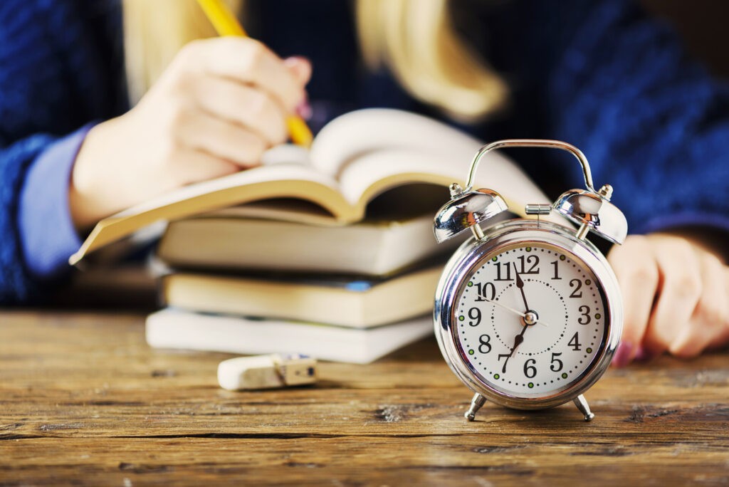 Reloj sobre mesa de estudio representando control del tiempo en oposiciones