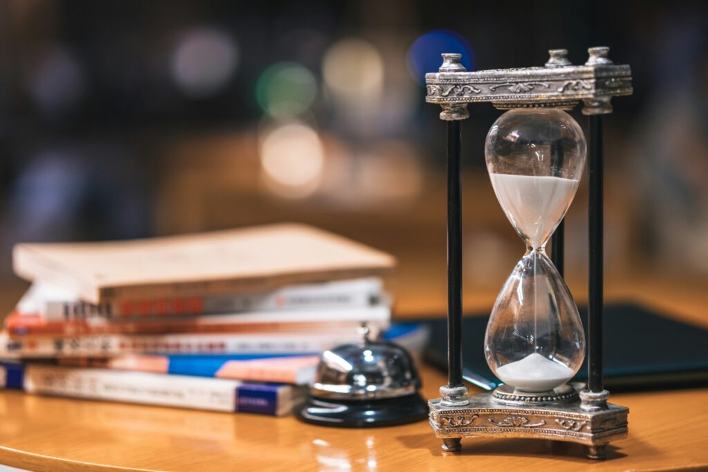 Reloj de arena con libros representando la organización del estudio en oposiciones